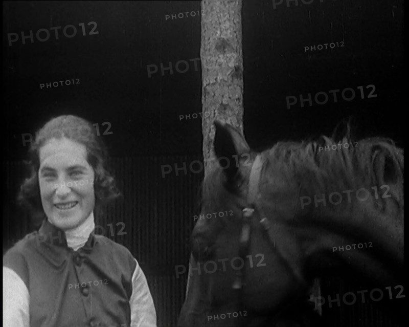A Female Civilian Wearing a Jockey's Outfit Removing Her Hat in Front of Her Horse and..., 1920. Creator: British Pathe Ltd.
