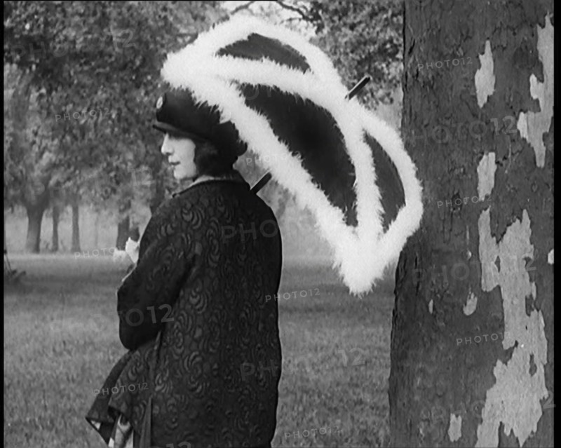 Female Civilian Dressed Glamorously Holding a Fur Trimmed Parasol in a Park, 1920. Creator: British Pathe Ltd.