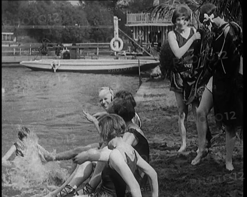 A Group of Young Female Civilians Wearing Swimsuits Playing on Riverside, 1920. Creator: British Pathe Ltd.