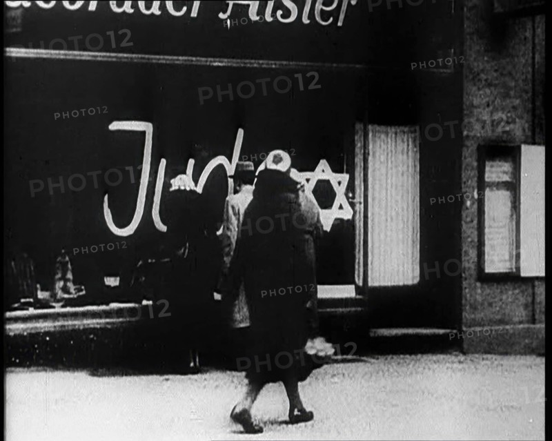 Civilians Looking at  Shop Window with Graffiti Reading: ‘Juden’ on it, 1933. Creator: British Pathe Ltd.