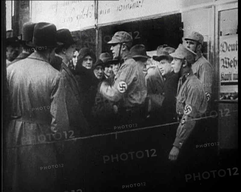 Men in Nazi Uniforms and Civilians Standing Outside a Shop With anti-Jewish Posters on it, 1933. Creator: British Pathe Ltd.