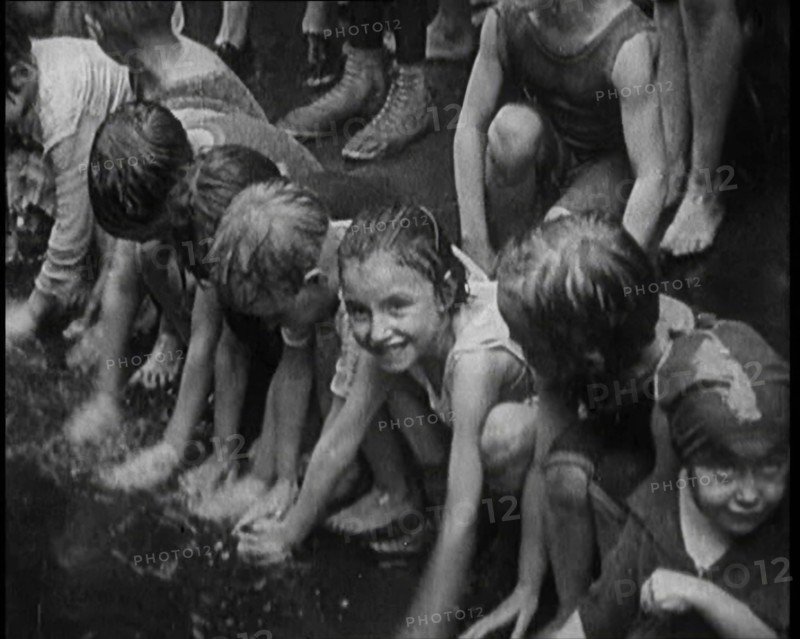 Children Splashing in Water in the Gutter During a Heatwave in New York City, 1921. Creator: British Pathe Ltd.