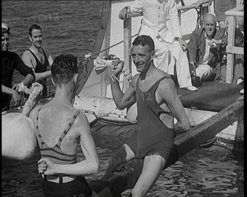 Two Male Civilians in Swim Suits Sitting on a Pole and Enjoying a Pillow Fight in Front..., 1931. Creator: British Pathe Ltd.