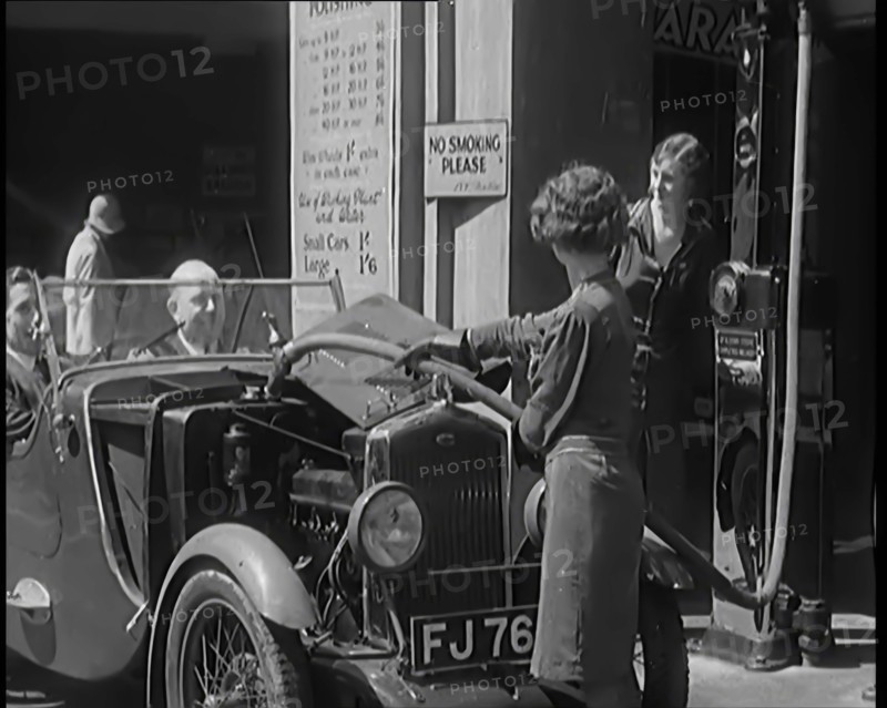 Female Civilians Working Petrol Pumps in a Garage and Filling up a Car, 1931. Creator: British Pathe Ltd.