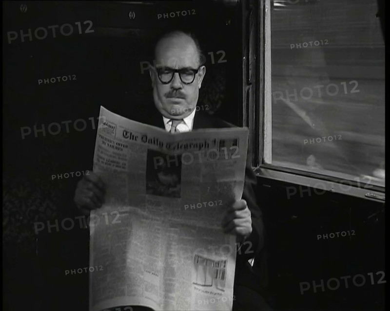 A Bald Man Wearing Spectacles Reading 'The Daily Telegraph' in the Carriage of a Train..., 1938. Creator: British Pathe Ltd.