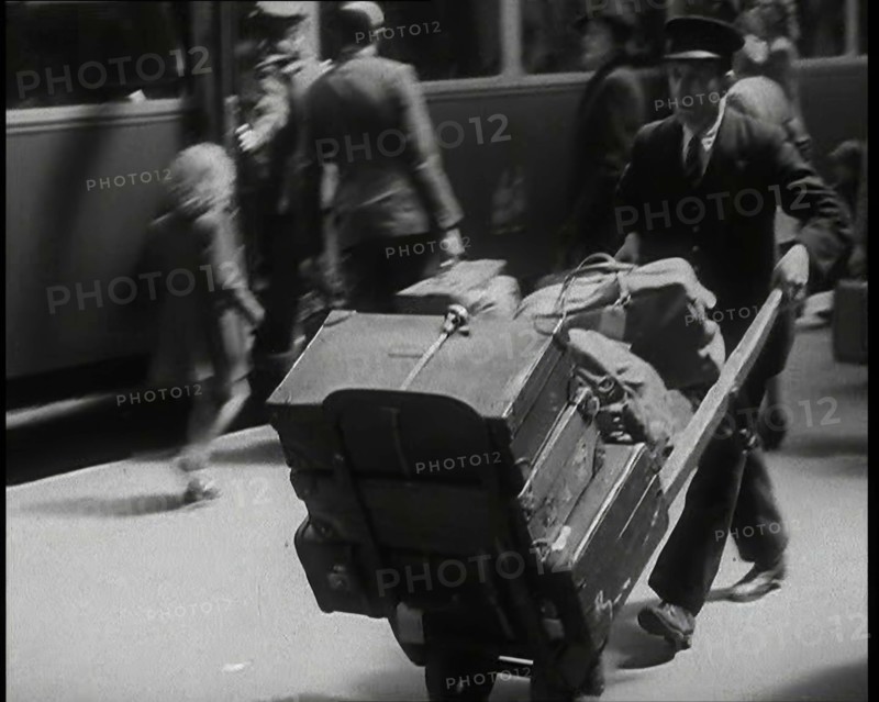 A Male Train Station Porter Pushing a Sack Barrow With Suitcases and Bags on it Along..., 1938. Creator: British Pathe Ltd.