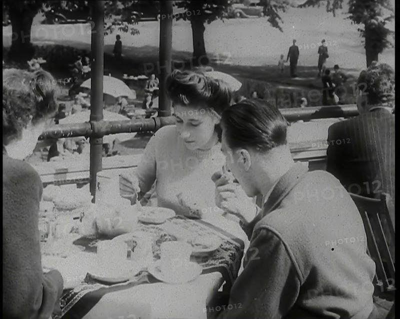 A Close up of Two Women and a Man Having Food and Drink on the Roof Terrace at  the Tea..., 1939. Creator: British Pathe Ltd.