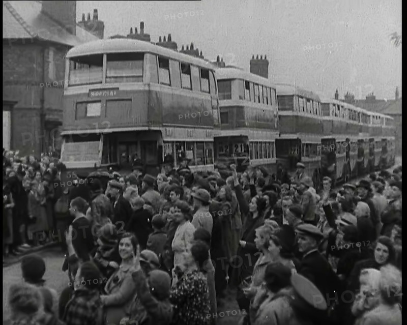 Men, Women, and Children Standing by a Line of Buses Parked in a Residential Street, 1939. Creator: British Pathe Ltd.