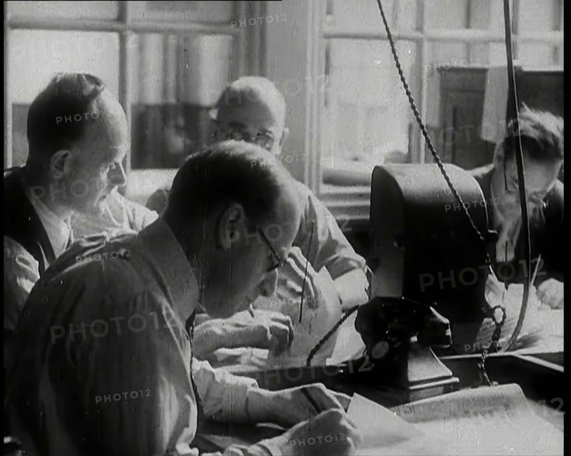 Four Male British Journalists Sitting Around a Table Covered in Papers and Writing, 1939. Creator: British Pathe Ltd.