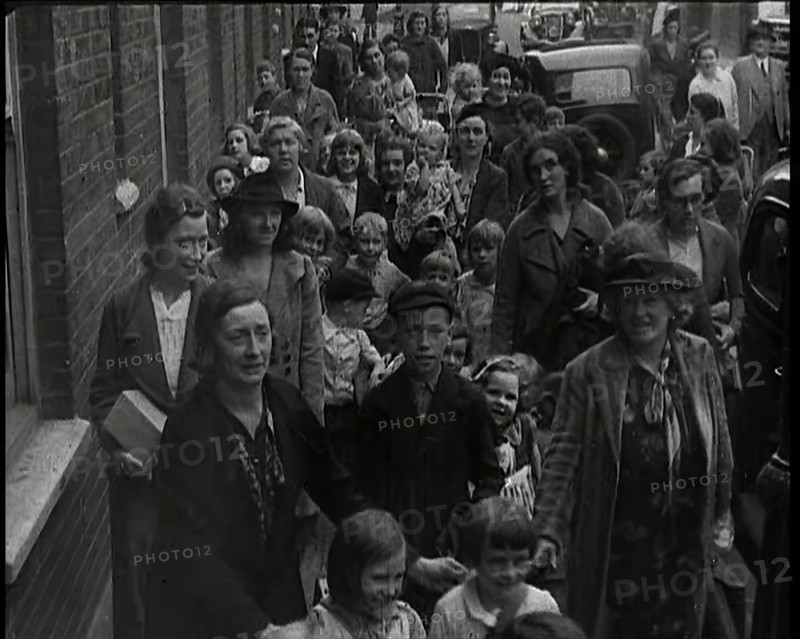 British Women and Child Evacuees Walking Along the Pavement of a Residential Street Next..., 1939. Creator: British Pathe Ltd.