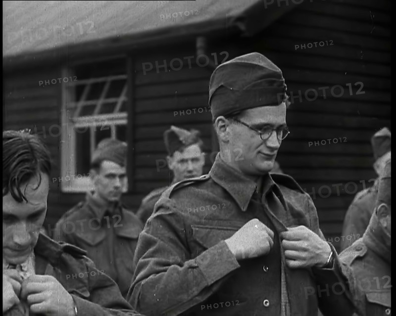 Close up on a Male British Soldier Wearing a Side Cap and Round-Rimmed Glasses Buttoning up..., 1939 Creator: British Pathe Ltd.