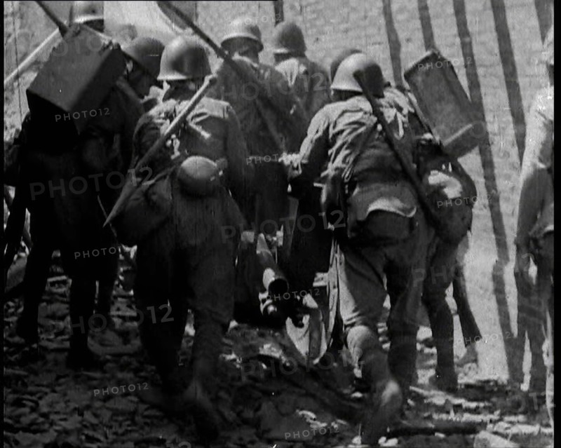 A Group of Male Japanese Soldiers Pushing a Gun Over Rubble in a Street in Shanghai, 1937. Creator: British Pathe Ltd.