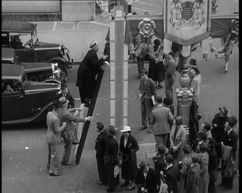 Bud Flanagan With a Frying Pan Climbing a Ladder Resting Against Coronation Decorations in..., 1937. Creator: British Pathe Ltd.