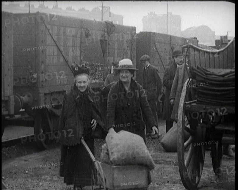 Two Elderly Female Civilians Wheeling a Barrow of Coal Away from a Railway Truck As Other..., 1924. Creator: British Pathe Ltd.