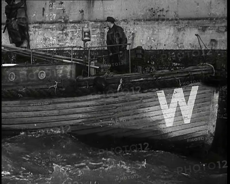 Small Wooden Customs Boat With Male Crew Member Standing at  the Bow End Alongside..., 1939. Creator: British Pathe Ltd.