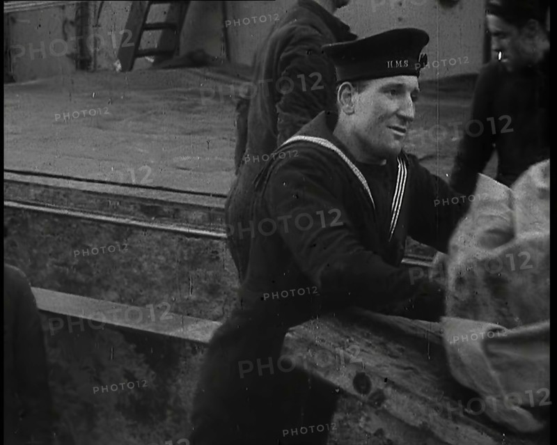 Several Male Crew, Including One from the Royal Navy, Inspecting the Cargo of a Large Vessel, 1939. Creator: British Pathe Ltd.
