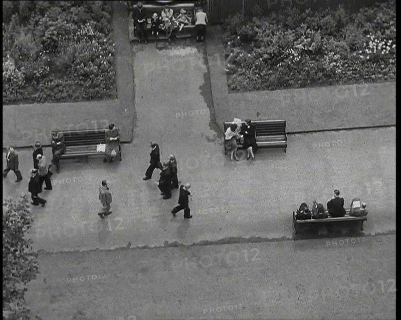 An Overhead Shot of Pedestrians Walking up and Down a Path or Sitting on Benches in a Park..., 1938. Creator: British Pathe Ltd.