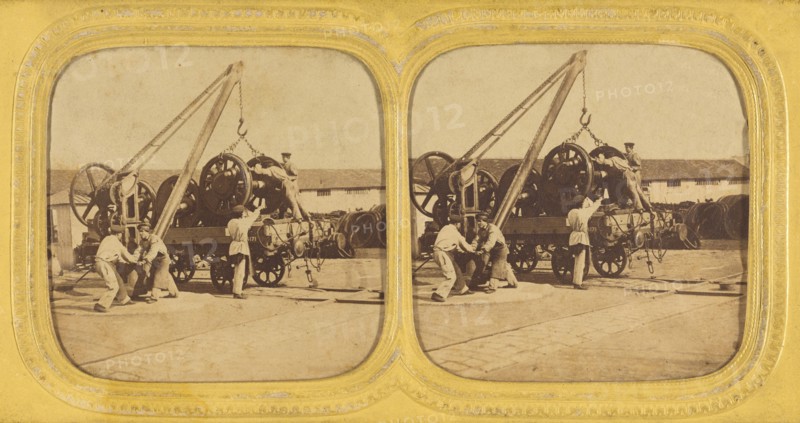 Men loading large iron wheels on platform, about 1865. Creator: Unknown.