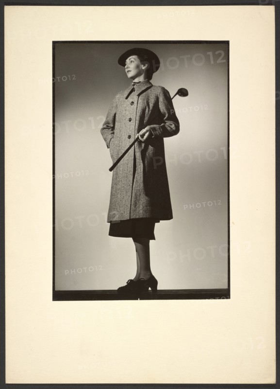 Woman modeling coat with golf club, early 1940s. Creator: Gunther Krampf.