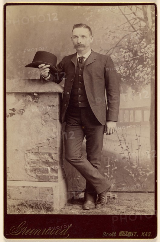 Studio portrait of a man holding a hat, about 1885. Creator: WH Greenwood.