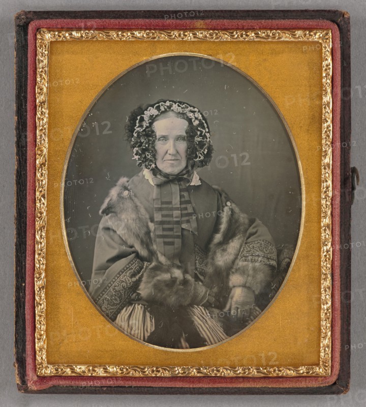 Portrait of an elderly woman wearing a hat, fur coat and gloves, seated, about 1855. Creator: Unknown.