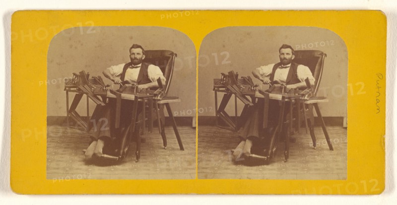 Portrait of Charles H. Barnes, Hardwick, Mass. seated in handicapped-style chair making ..., 1870s. Creator: George T Putnam.