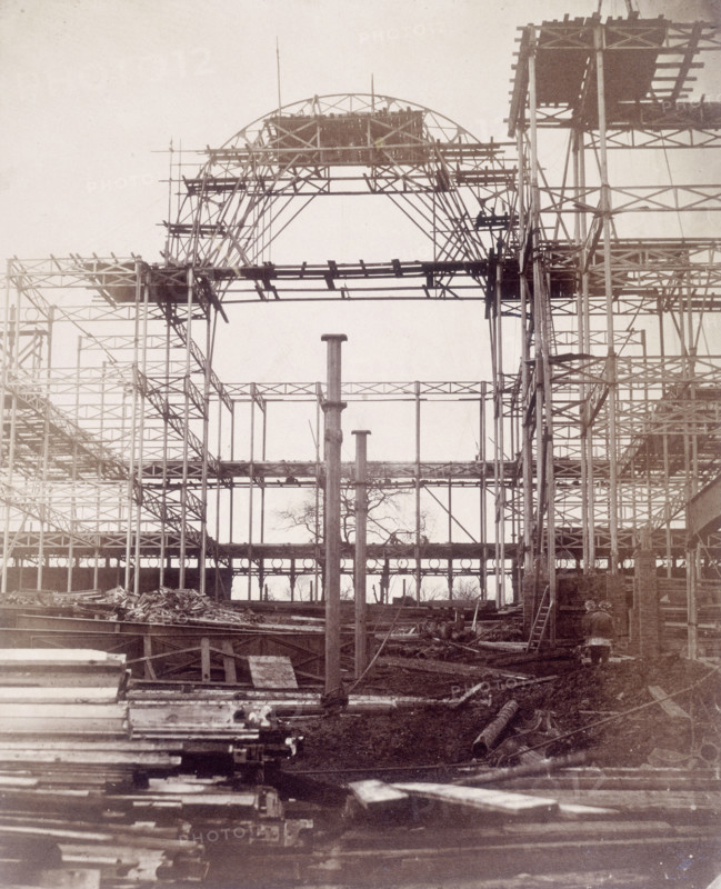 'First rib of the Nave, October 1852', Crystal Palace, London. Designed by Sir Joseph Paxton to house the Great Exhibition of 1851 in Hyde Park, the Crystal Palace was reconstructed and enlarged in Sydenham in 1852. The first column was raised on 5 August 1852 and the palace was opened by Queen Victoria on 10 June 1854. Many exhibitions and events were subsequently held at the Crystal Palace until it burnt down on 30 November 1936. The park contained a motor racing circuit from 1937 until 1972 and the famous athletics track dates back to the foundation of the Crystal Palace Athletics Club in 1868. Plate 5 from "Photographic Views of the Progress of the Crystal Palace, Sydenham. Taken during the progress of the works, by desire of the directors, by Philip H Delamotte. Together with a list of the directors and officers of the company, etc". [London, 1855].