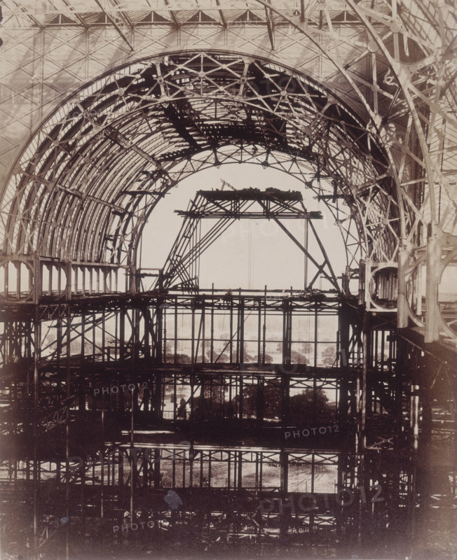 'South Transept looking towards Penge', Crystal Palace, Sydenham, 1852-1854. Designed by Sir Joseph Paxton to house the Great Exhibition of 1851 in Hyde Park, the Crystal Palace was reconstructed and enlarged in Sydenham in 1852. The first column was raised on 5 August 1852 and the palace was opened by Queen Victoria on 10 June 1854. Many exhibitions and events were subsequently held at the Crystal Palace until it burnt down on 30 November 1936. The park contained a motor racing circuit from 1937 until 1972 and the famous athletics track dates back to the foundation of the Crystal Palace Athletics Club in 1868. Plate 18 from "Photographic Views of the Progress of the Crystal Palace, Sydenham. Taken during the progress of the works, by desire of the directors, by Philip H Delamotte. Together with a list of the directors and officers of the company, etc". [London, 1855].