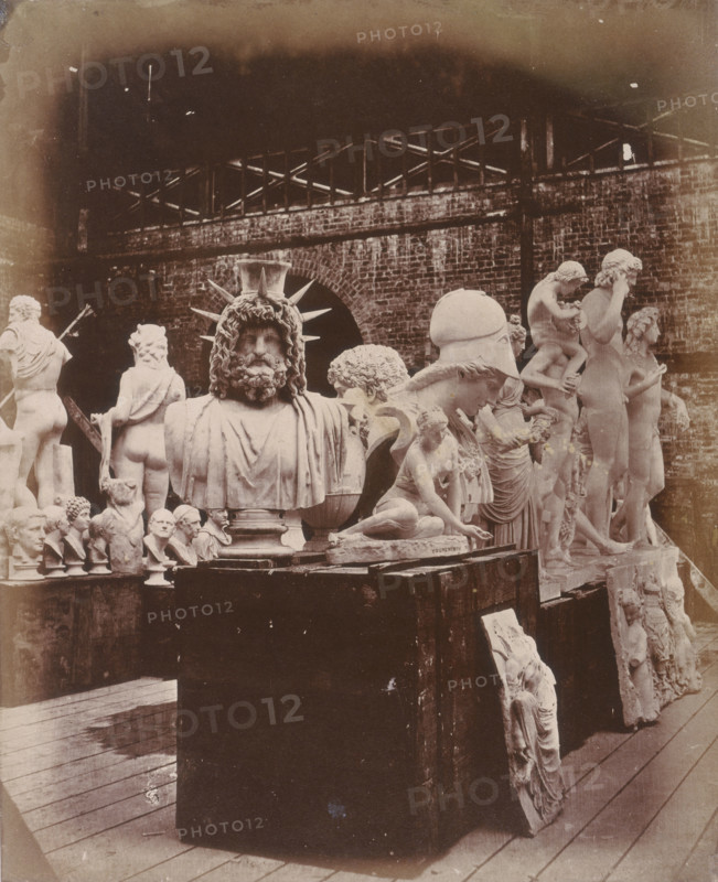 'Group of Sculpture in the Roman Court', Crystal Palace, Sydenham, 1852-1854. Designed by Sir Joseph Paxton to house the Great Exhibition of 1851 in Hyde Park, the Crystal Palace was reconstructed and enlarged in Sydenham in 1852. The first column was raised on 5 August 1852 and the palace was opened by Queen Victoria on 10 June 1854. Many exhibitions and events were subsequently held at the Crystal Palace until it burnt down on 30 November 1936. The park contained a motor racing circuit from 1937 until 1972 and the famous athletics track dates back to the foundation of the Crystal Palace Athletics Club in 1868. Plate 19 from "Photographic Views of the Progress of the Crystal Palace, Sydenham. Taken during the progress of the works, by desire of the directors, by Philip H Delamotte. Together with a list of the directors and officers of the company, etc". [London, 1855].