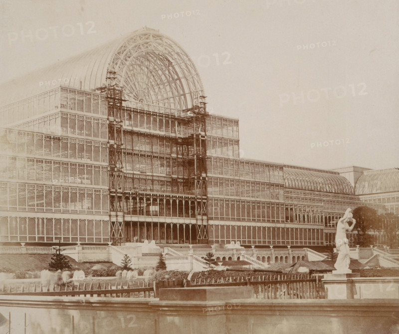 'The Centre Transept - from the Garden', Crystal Palace, Sydenham, 1852-1854.  Designed by Sir Joseph Paxton to house the Great Exhibition of 1851 in Hyde Park, the Crystal Palace was reconstructed and enlarged in Sydenham in 1852. The first column was raised on 5 August 1852 and the palace was opened by Queen Victoria on 10 June 1854. Many exhibitions and events were subsequently held at the Crystal Palace until it burnt down on 30 November 1936. The park contained a motor racing circuit from 1937 until 1972 and the famous athletics track dates back to the foundation of the Crystal Palace Athletics Club in 1868. Plate 67 from "Photographic Views of the Progress of the Crystal Palace, Sydenham. Taken during the progress of the works, by desire of the directors, by Philip H Delamotte. Together with a list of the directors and officers of the company, etc". [London, 1855].