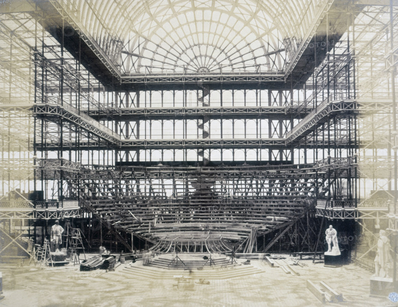 'Erection of the Orchestra for the Opening Ceremony', Crystal Palace, Sydenham, 1852-1854. Designed by Sir Joseph Paxton to house the Great Exhibition of 1851 in Hyde Park, the Crystal Palace was reconstructed and enlarged in Sydenham in 1852. The first column was raised on 5 August 1852 and the palace was opened by Queen Victoria on 10 June 1854. Many exhibitions and events were subsequently held at the Crystal Palace until it burnt down on 30 November 1936. The park contained a motor racing circuit from 1937 until 1972 and the famous athletics track dates back to the foundation of the Crystal Palace Athletics Club in 1868. Plate 85 from "Photographic Views of the Progress of the Crystal Palace, Sydenham. Taken during the progress of the works, by desire of the directors, by Philip H Delamotte. Together with a list of the directors and officers of the company, etc". [London, 1855].