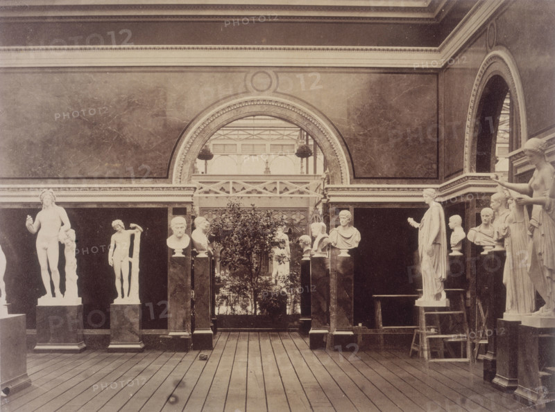 'Interior of the Roman Court', Crystal Palace, Sydenham, 1852-1854. Designed by Sir Joseph Paxton to house the Great Exhibition of 1851 in Hyde Park, the Crystal Palace was reconstructed and enlarged in Sydenham in 1852. The first column was raised on 5 August 1852 and the palace was opened by Queen Victoria on 10 June 1854. Many exhibitions and events were subsequently held at the Crystal Palace until it burnt down on 30 November 1936. The park contained a motor racing circuit from 1937 until 1972 and the famous athletics track dates back to the foundation of the Crystal Palace Athletics Club in 1868. Plate 91 from "Photographic Views of the Progress of the Crystal Palace, Sydenham. Taken during the progress of the works, by desire of the directors, by Philip H Delamotte. Together with a list of the directors and officers of the company, etc". [London, 1855].