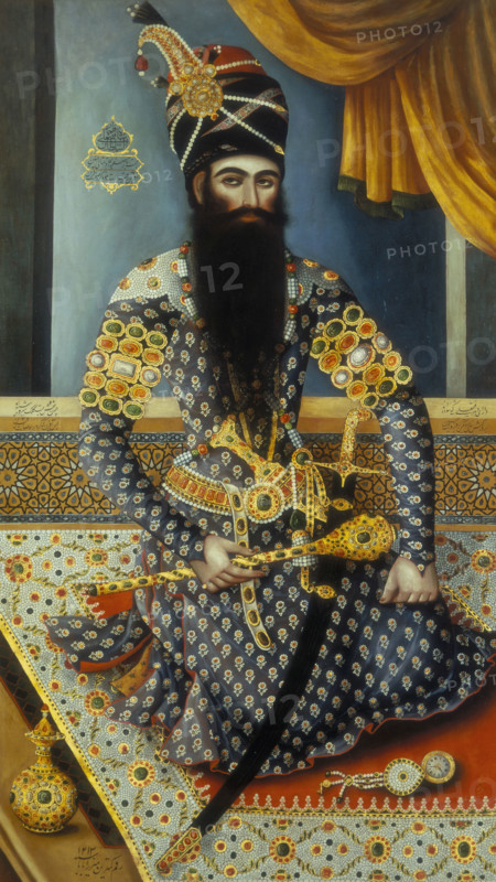 Fath Ali Shah, the Shah of Persia, (c1800?). The Shah is splendidly dressed, with a jewelled turban and weapons and a thick beard. He is seated on a carpet, with a small pocket watch in front of him.