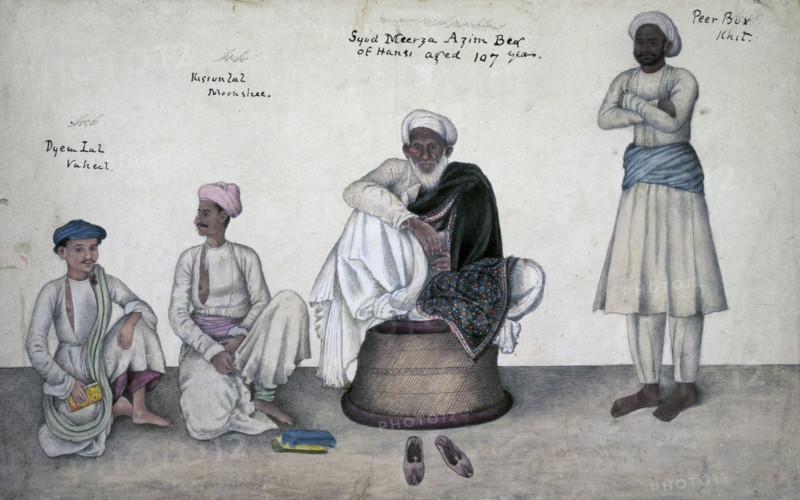 Portrait of Saiyid Mirza Azim Beg of Hansi, 1820-1830. Saiyid Mirza Azim Beg of Hansi (Syud Meerza Azim Beg of Hansi aged 107 years) seated on a cane stool with Dai Lal Vakil (Dyem Lal, Vukeel), Kisan Lal Munshi (Kissun Lal, Moonshee) and Pir Bakhsh Khitmatgar (Peer Bux, Khit). Indian centenarian dressed in white and wearing a black embroidered Kashmir shawl. Also inscribed in Persian characters. From the Skinner Album.