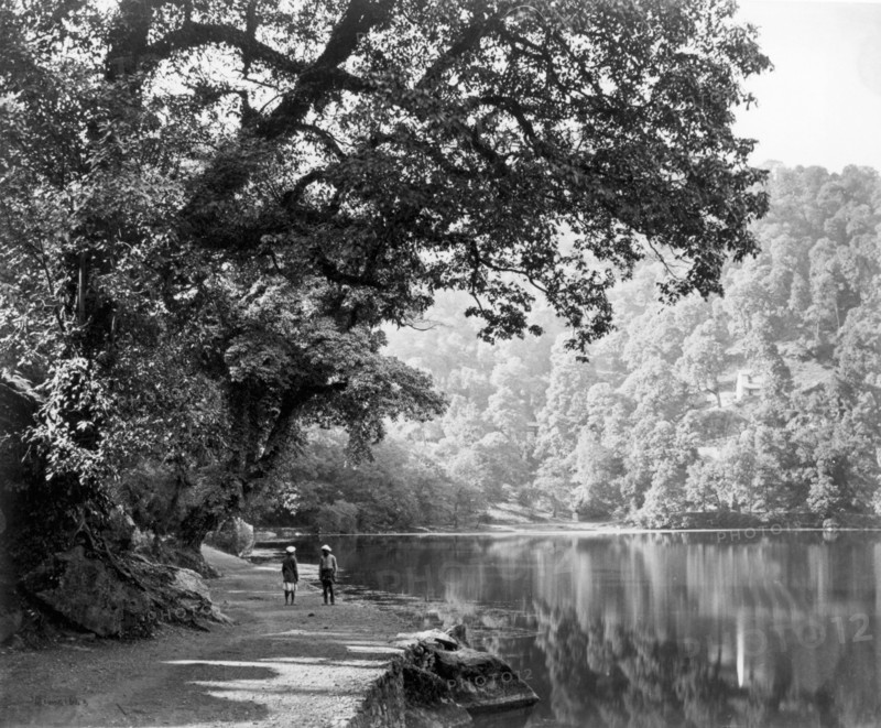 Lake at Naini Tal, India, c1865. Two people stand on the shore beside this picturesque, tree-lined lake. Naini Tal was a hill station in the Kumaon Hills of northern India.