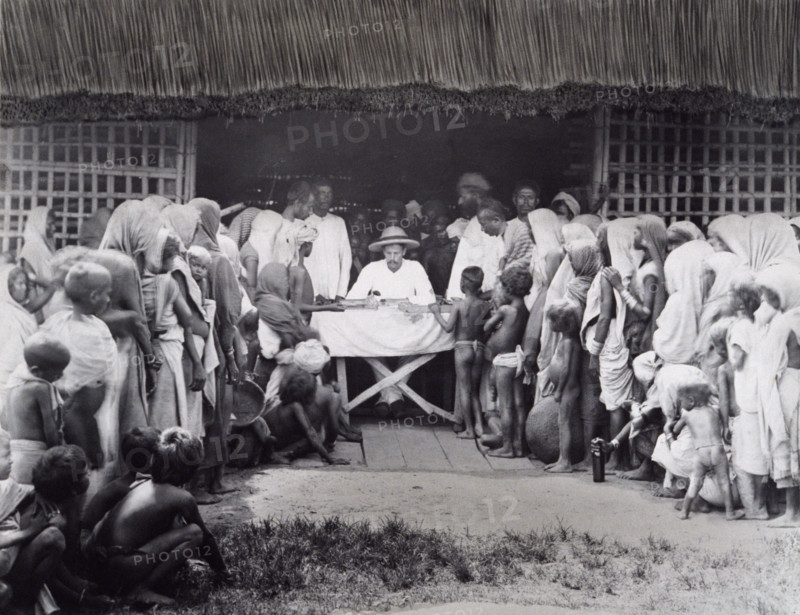 Paying wages to tea estate labourers, Bengal, 1880s. A European distributes pay to Indian workers, some of whom are young near-naked children.
