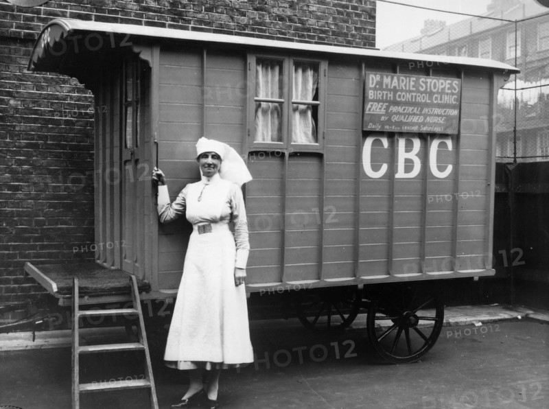 Nurse outside a Marie Stopes mobile birth control clinic, Bethnal Green, London, 1928. 'Free practical instruction by qualified nurse'. In 1921, Dr Marie Stopes founded the first birth control clinic in Britain. In order to make advice on birth control available in working class areas and rural districts, Dr Stopes also established mobile clinics in caravans, such as this one. However Stopes' ideas about eugenics were controversial: according to some she was 'an elitist, an idealist, interested in creating a society in which only the best and beautiful should survive'.