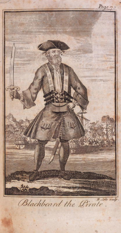 'Blackbeard the Pirate'. 1724. The engraving shows Blackbeard in costume, heavily armed and holding a sabre. In the background are ships at anchor. From "A General History of the Robberies and Murders of the most Notorious Pyrates, and also their policies, discipline and government, from their first rise and settlement in the island of Providence, in 1717, to the present year 1724. With the remarkable actions and adventures of the two female pyrates, Mary Read and Anne Bonny. To which is prefix'd an account of the famous Captain Avery ...To which is added, a short abstract of the statute and civil law, in relation to pyracy. By Captain Charles Johnson" by Charles Johnson (pseudonym of Daniel Defoe). (London, 1724).