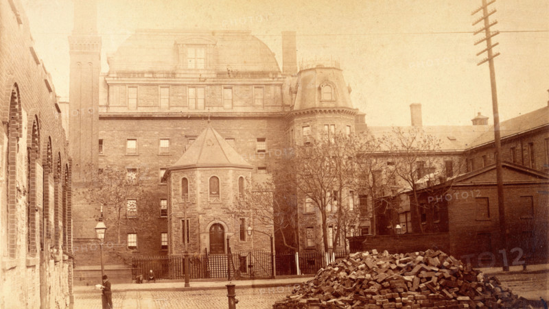Bellevue Hospital, New York City: hospital buildings with a tower; a pile of bricks in the fore... Creator: Unknown.