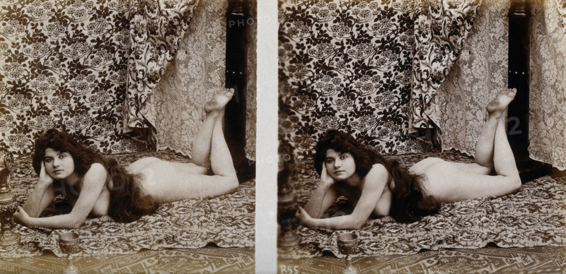 A young woman posing naked in a photographic studio, lying on her front on a piece of..., c1900. Creator: Unknown.