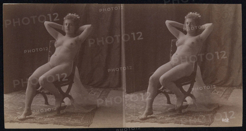 A young woman posing naked but for a long veil, leaning back in a chair, in a photographic..., c1900 Creator: Unknown.