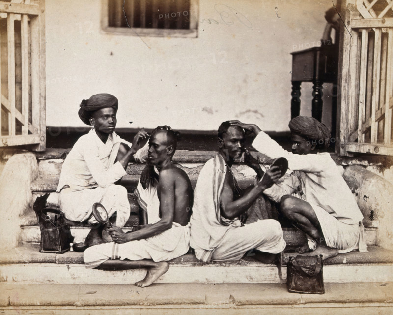Two Indian barbers wearing turbans shaving the heads of two Indian men..., c1900s. Creator: Unknown.
