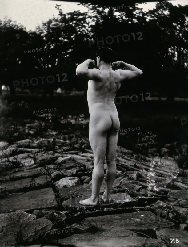 A man posing naked, with his back to the camera, standing on a rocky outcrop, c1900. Creator: Unknown.