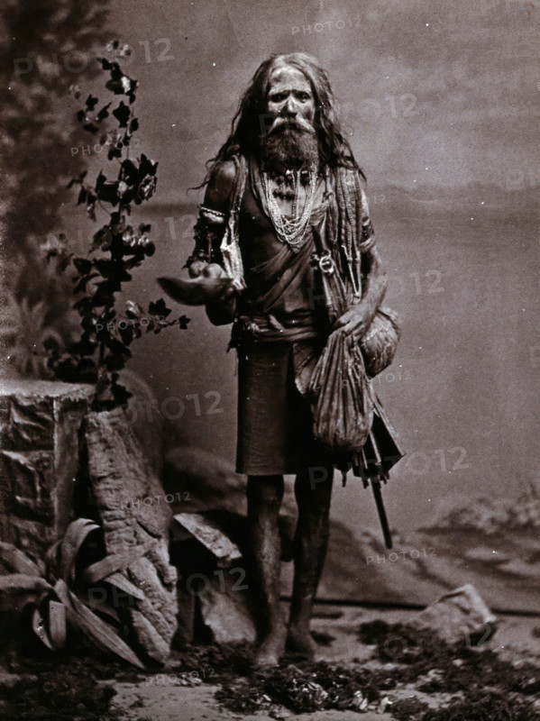 An Indian man wearing many beads, and carrying a begging bowl and an umbrella, in a..., c1900. Creator: Unknown.
