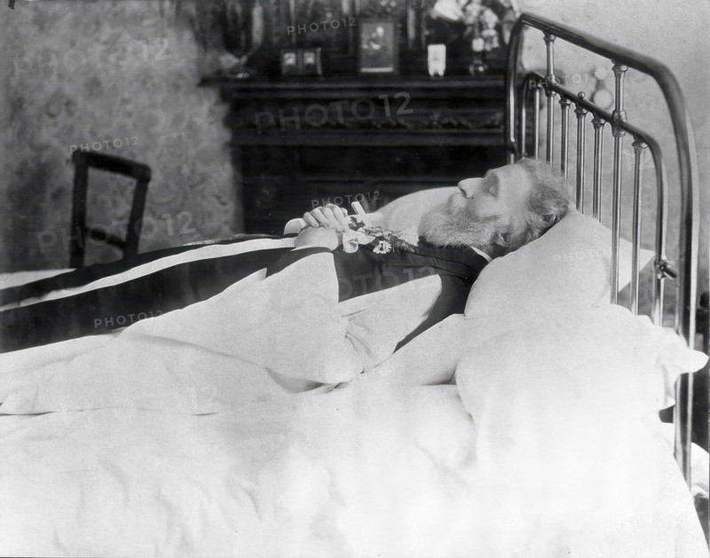 A dead man, wearing robes, lying on his deathbed, (1900?). Creator: Unknown.