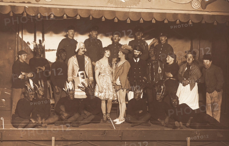 Soldiers, some in drag, pose on stage; two men in drag face each other in the centre, [1910-1919?]. Creator: Unknown.