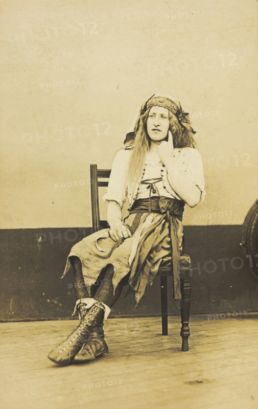 A man in drag sits pensively on a chair, on the deck of a ship, (between 1910 and 1919?). Creator: Unknown.