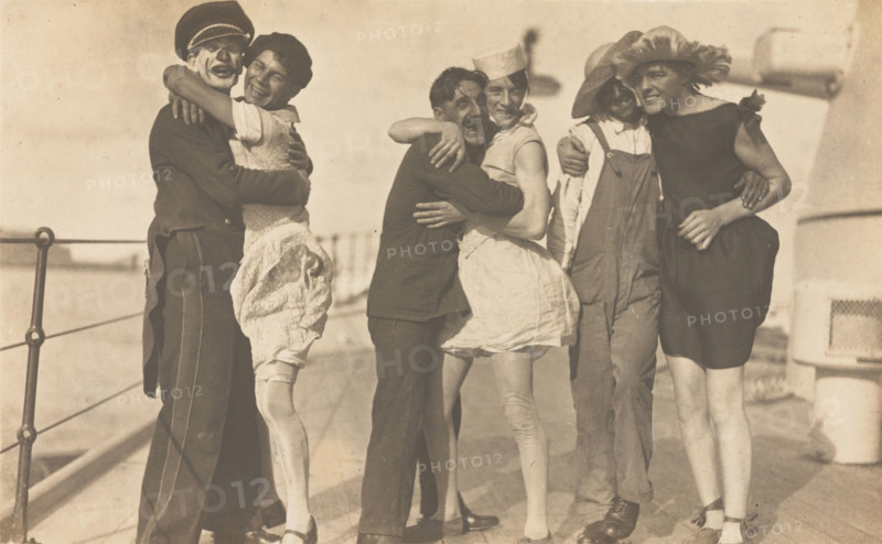 Sailors, some in drag, pose as three couples on the deck of a ship, (between 1920 and 1929?). Creator: Unknown.