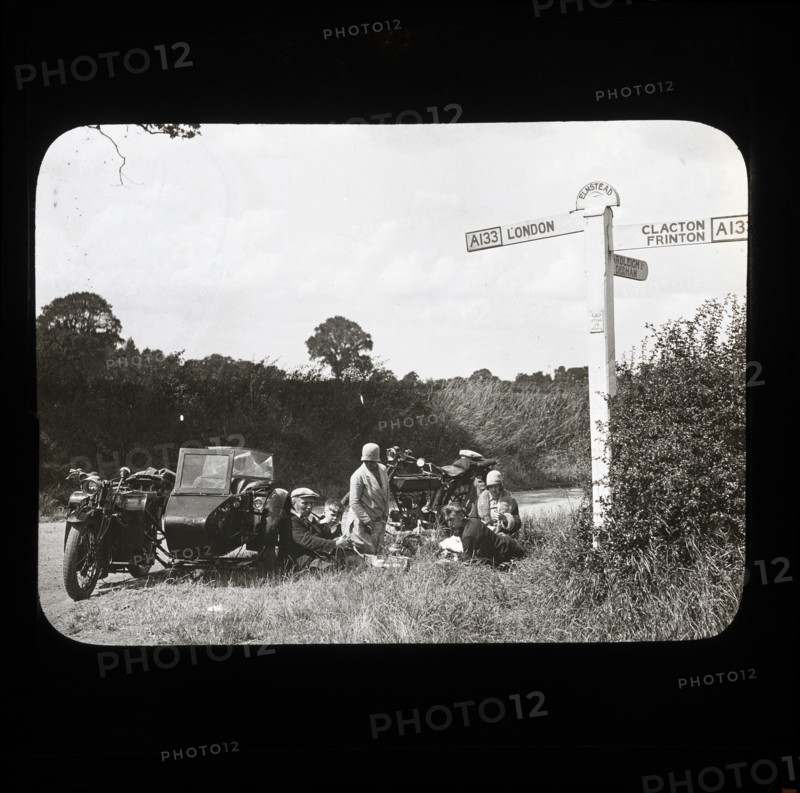 A group of people with two motorcycles and a sidecar having a picnic at the side of..., 1926-1939.  Creator: Norman Kingsley Harrison.
