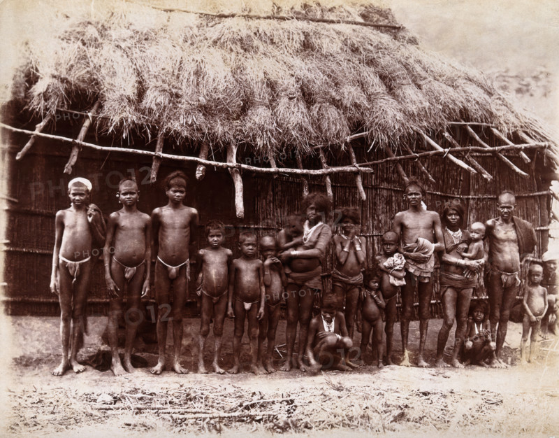 A group of adults and children standing in a line outside a bamboo hut with a thatched..., 1896/1897 Creator: Unknown.